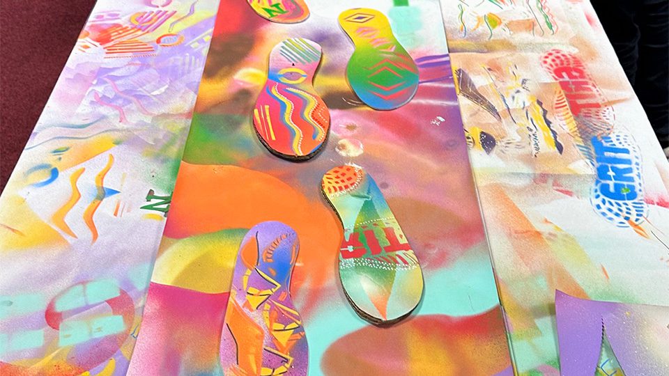 Spray painted footprints on a spray painted canvas laid out on a street art workshop table